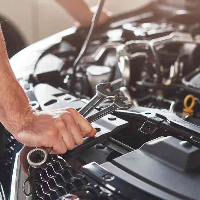 Mecánico con llave revisando motor de vehículo JAC.
